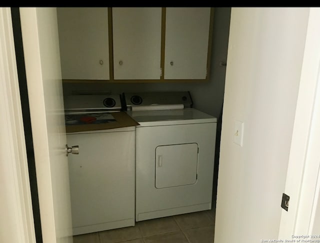 clothes washing area featuring washer and dryer, cabinets, and light tile patterned floors