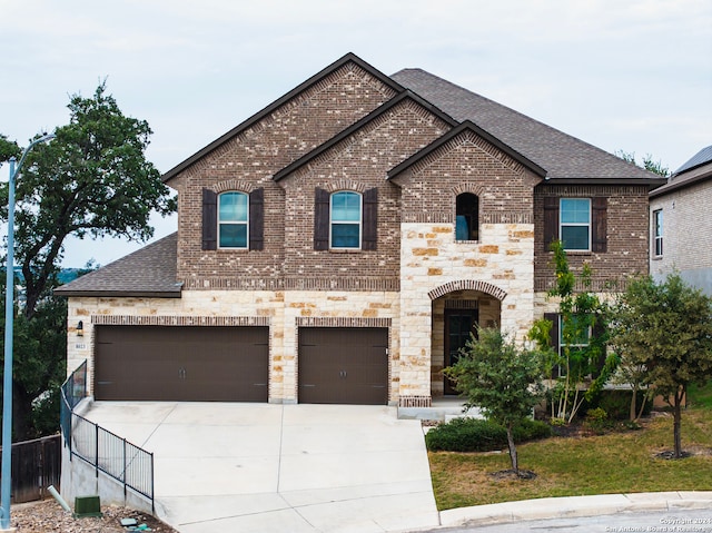 french country style house featuring concrete driveway, brick siding, roof with shingles, and stone siding