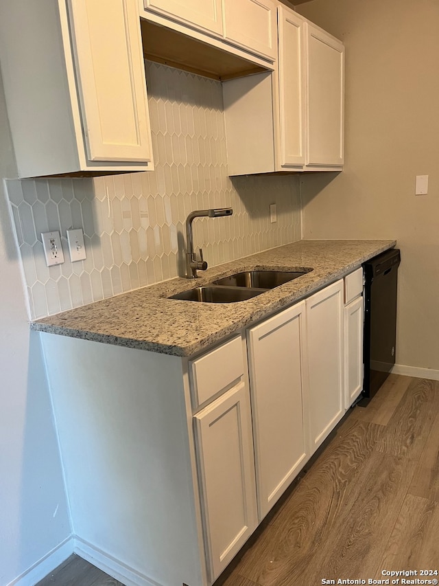 kitchen with decorative backsplash, sink, hardwood / wood-style flooring, dishwasher, and white cabinetry