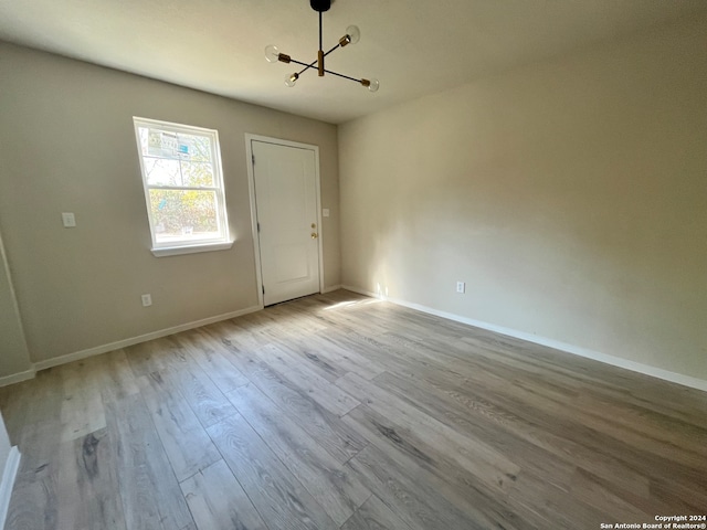 empty room with a notable chandelier and light wood-type flooring