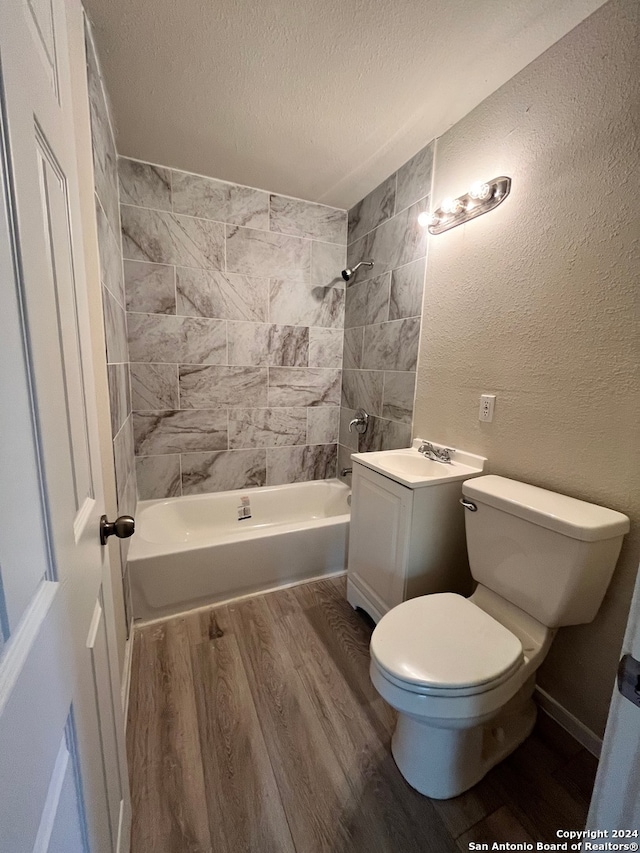 full bathroom featuring a textured ceiling, vanity, tiled shower / bath combo, hardwood / wood-style flooring, and toilet