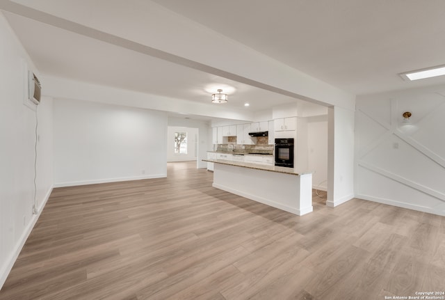 unfurnished living room featuring a wall unit AC and light hardwood / wood-style flooring