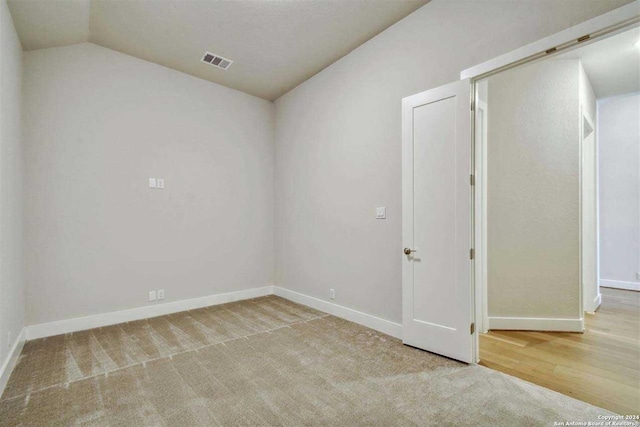 carpeted spare room with lofted ceiling