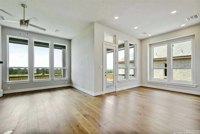 empty room with ceiling fan, plenty of natural light, and light hardwood / wood-style floors