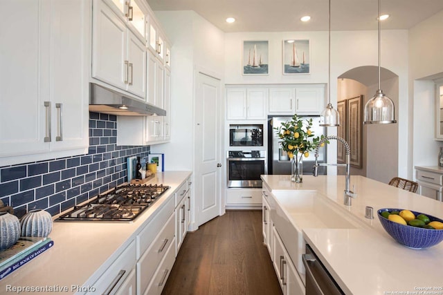 kitchen featuring sink, hanging light fixtures, stainless steel appliances, tasteful backsplash, and white cabinets