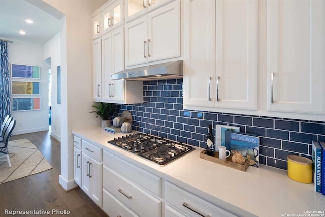 kitchen with tasteful backsplash, dark wood-type flooring, stainless steel gas stovetop, and white cabinets