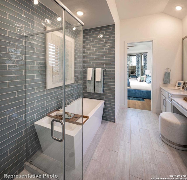 bathroom with tile walls, vanity, lofted ceiling, and shower with separate bathtub