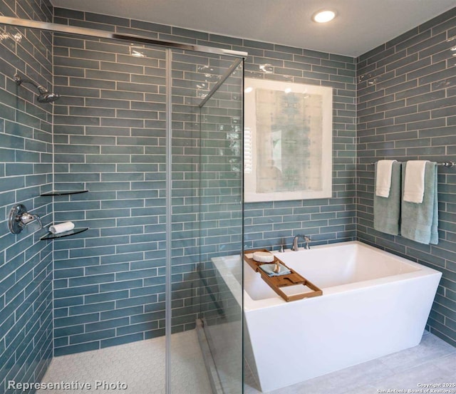 bathroom featuring shower with separate bathtub and tile walls