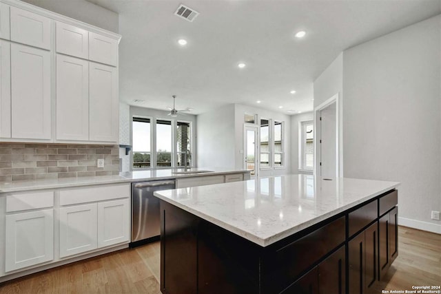 kitchen with white cabinetry, dishwasher, sink, decorative backsplash, and a center island