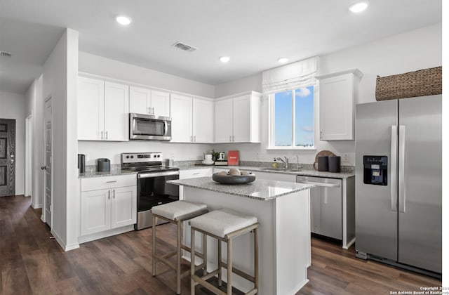8156 Smithers Ave, San Antonio, TX 78252 - kitchen featuring appliances with stainless steel finishes, white cabinetry, dark wood finished floors, a center island, and recessed lighting