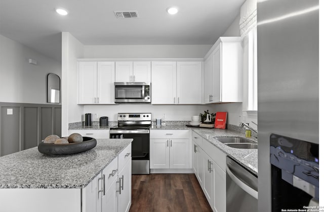 8156 Smithers Ave, San Antonio, TX 78252 - kitchen with stainless steel appliances, white cabinets, a kitchen island, light stone countertops, and recessed lighting