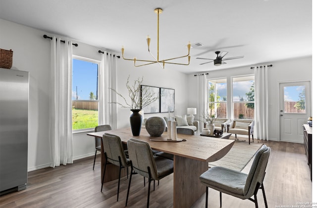 dining area with dark hardwood / wood-style flooring, a healthy amount of sunlight, and ceiling fan with notable chandelier