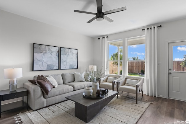 living room with plenty of natural light, ceiling fan, and dark wood-type flooring