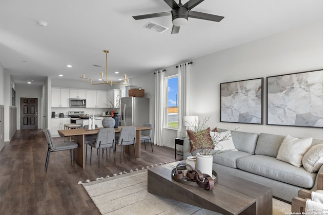 living room with ceiling fan with notable chandelier and dark wood-type flooring