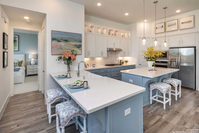 kitchen featuring appliances with stainless steel finishes, a breakfast bar, white cabinets, hanging light fixtures, and kitchen peninsula