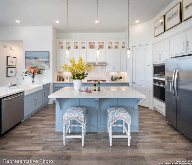 kitchen with a kitchen island, sink, white cabinets, a kitchen breakfast bar, and stainless steel appliances