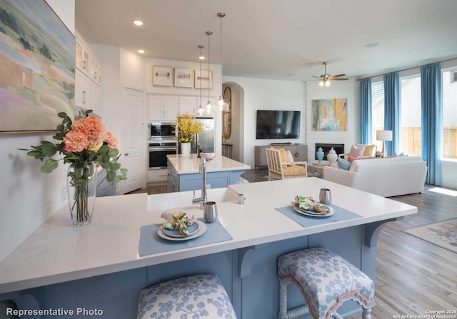 kitchen with hanging light fixtures, a kitchen bar, a large island with sink, and appliances with stainless steel finishes