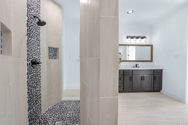 bathroom with tile patterned flooring, vanity, and tiled shower