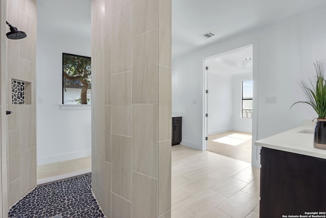 bathroom featuring tile patterned flooring, vanity, and tiled shower