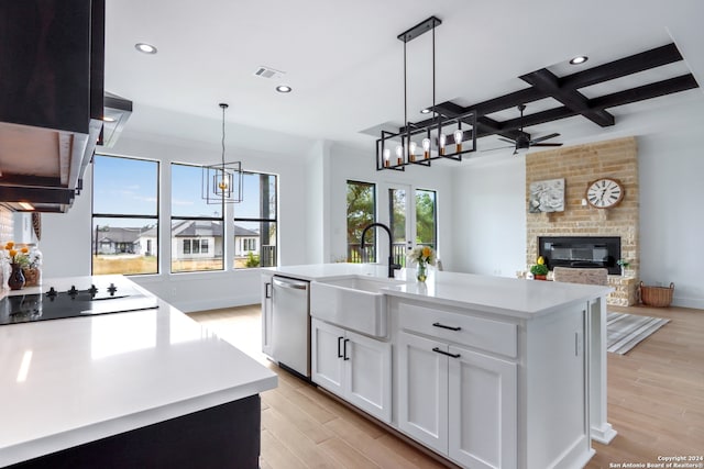 kitchen featuring white cabinets, light wood-type flooring, stainless steel dishwasher, and an island with sink