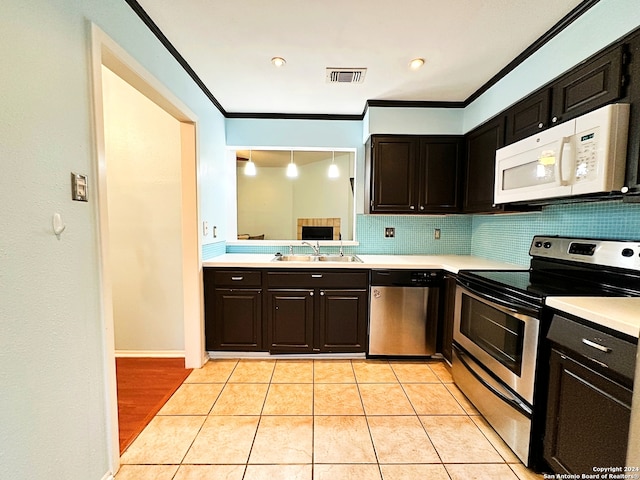 kitchen with light tile patterned flooring, ornamental molding, appliances with stainless steel finishes, and tasteful backsplash