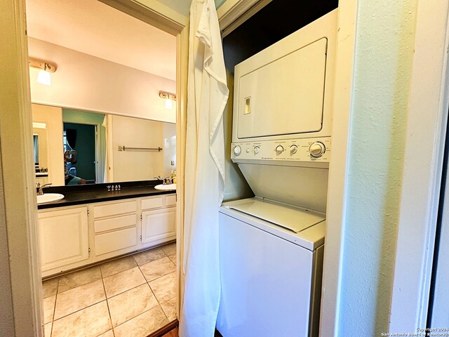 washroom with sink, light tile patterned floors, and stacked washer / drying machine