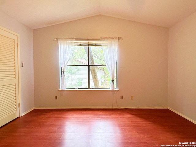 unfurnished bedroom featuring lofted ceiling, wood finished floors, and baseboards
