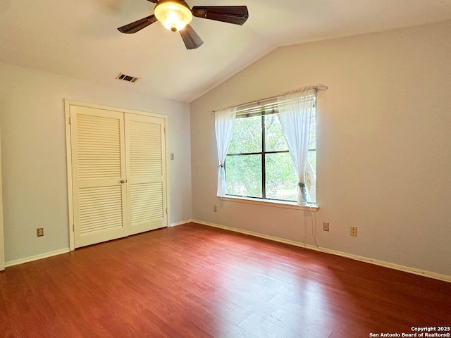 unfurnished bedroom with lofted ceiling, wood finished floors, visible vents, and baseboards