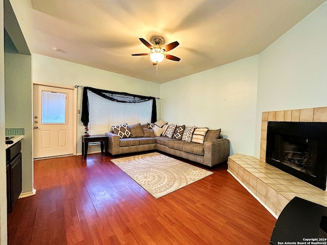 living room featuring a tiled fireplace, ceiling fan, and wood-type flooring