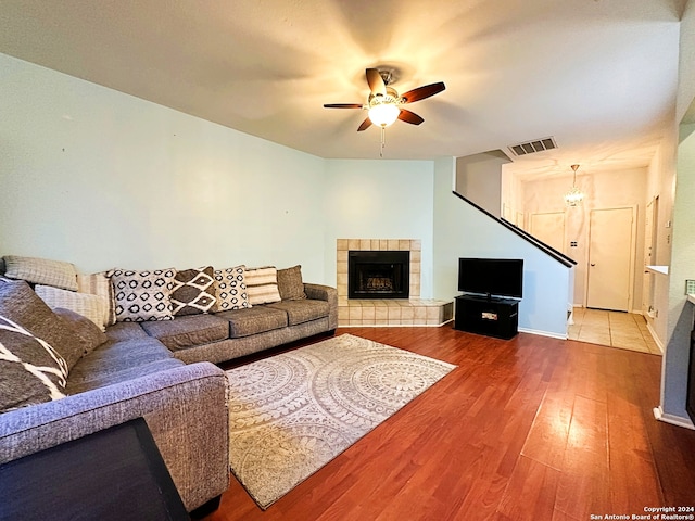 living room featuring hardwood / wood-style flooring, ceiling fan, and a tiled fireplace