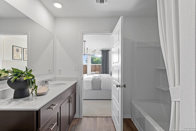 bathroom with shower / bathtub combination with curtain, vanity, and wood-type flooring