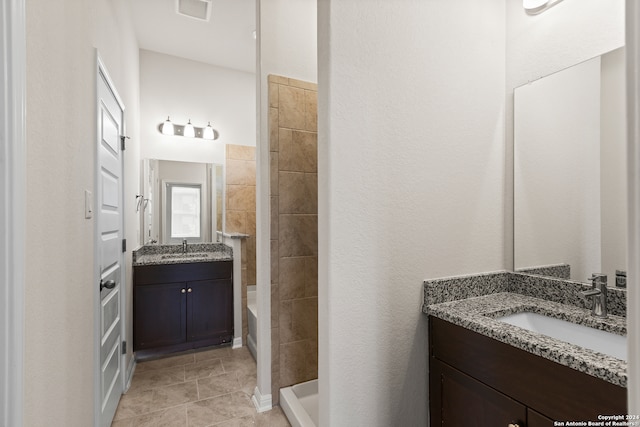 bathroom featuring tile patterned flooring, vanity, and a tile shower