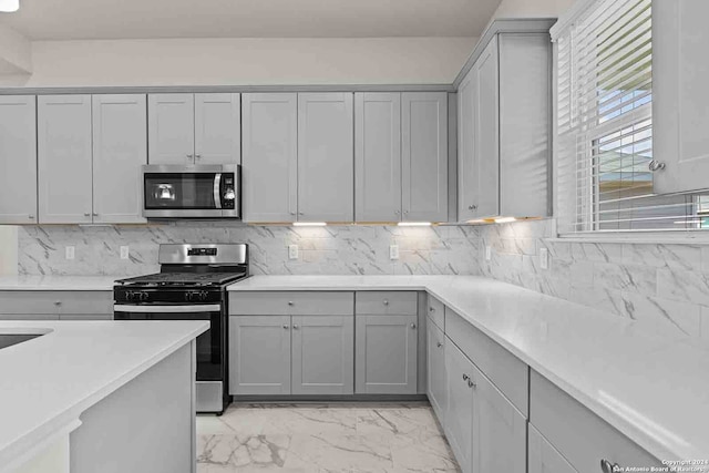 kitchen featuring tasteful backsplash, gray cabinets, and appliances with stainless steel finishes