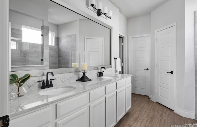 bathroom with tiled shower, vanity, and hardwood / wood-style flooring