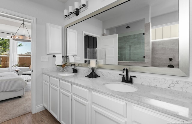 bathroom with hardwood / wood-style floors, vanity, and a tile shower