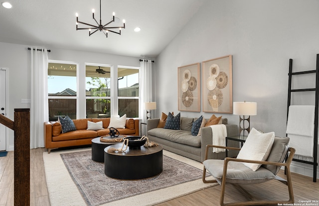 living room with high vaulted ceiling, an inviting chandelier, and light hardwood / wood-style flooring