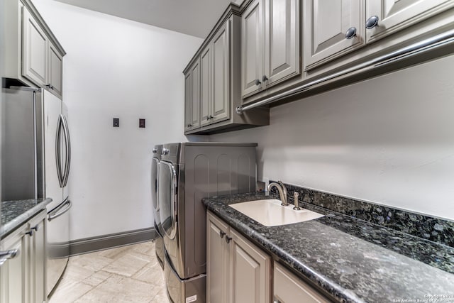 clothes washing area featuring washer and dryer, cabinets, and sink