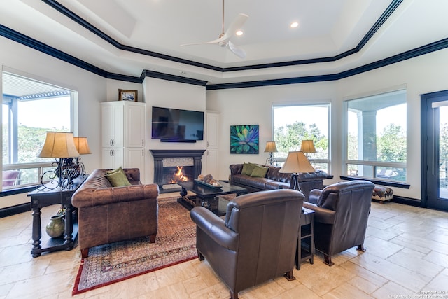 living room with ceiling fan, a raised ceiling, and ornamental molding