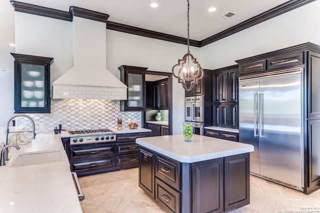 kitchen with sink, hanging light fixtures, stainless steel appliances, custom range hood, and ornamental molding