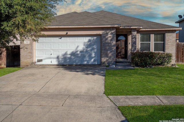 ranch-style home featuring a lawn and a garage