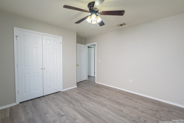 unfurnished bedroom with ceiling fan, a closet, and light wood-type flooring