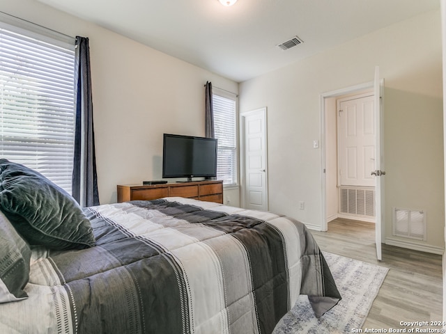 bedroom with multiple windows and light wood-type flooring