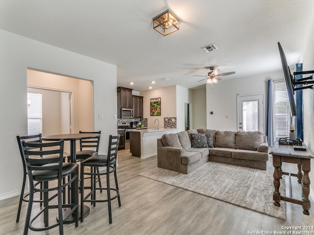 living room featuring light wood-type flooring, ceiling fan, and sink