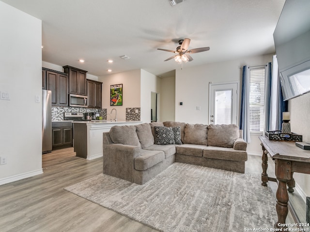 living room with ceiling fan, sink, and light hardwood / wood-style flooring