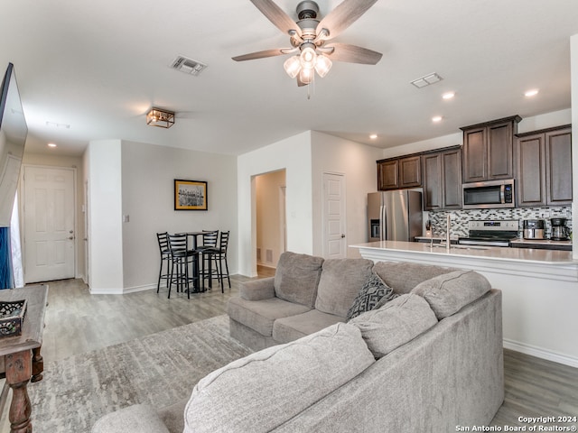 living room featuring ceiling fan, sink, and light hardwood / wood-style flooring