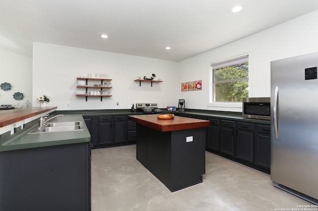 kitchen with appliances with stainless steel finishes, a center island, butcher block countertops, and sink