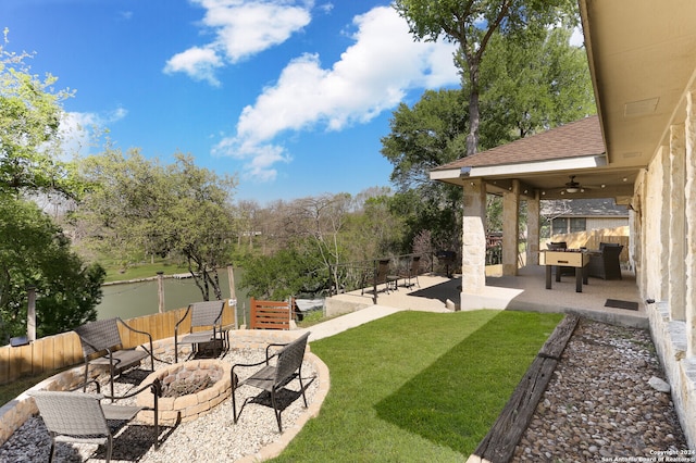 view of yard featuring a water view, ceiling fan, a patio area, and an outdoor living space with a fire pit