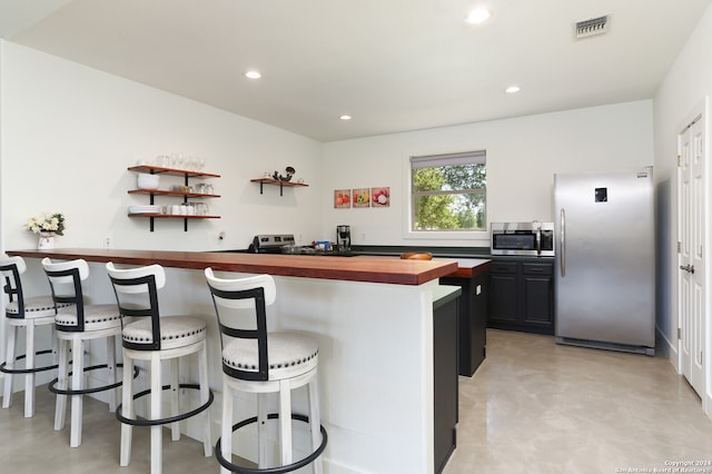 kitchen featuring butcher block countertops, a breakfast bar area, and appliances with stainless steel finishes