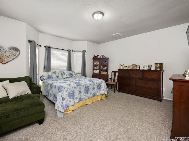 bedroom featuring light carpet and a textured ceiling