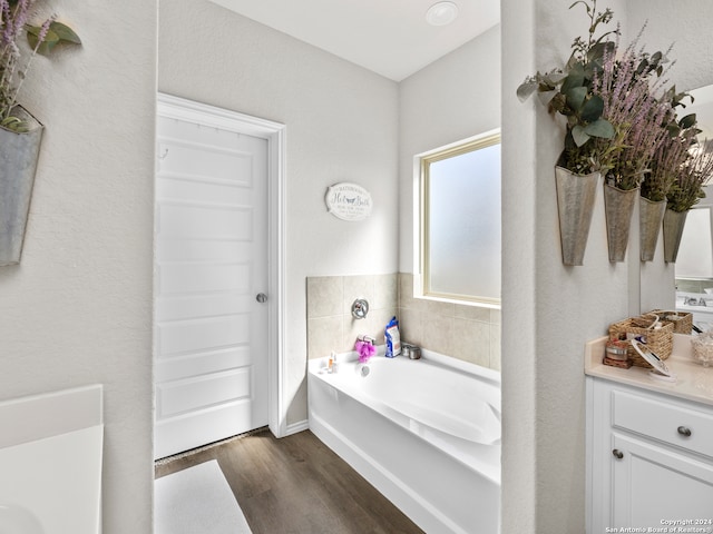 bathroom with a washtub, wood-type flooring, and vanity